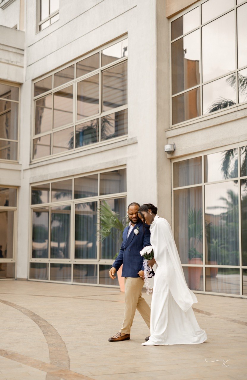 Claudine and Edward walking together outside in their wedding attire